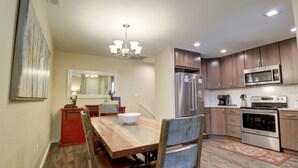 A modern kitchen with wooden cabinets, stainless steel appliances, and a dining area with a wooden table and chairs. - 201 Point Drive 2 Bedroom Condo by RedAwning (Frisco)