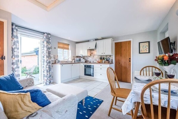 Cozy living space with a sofa set, dining table, and kitchenette.