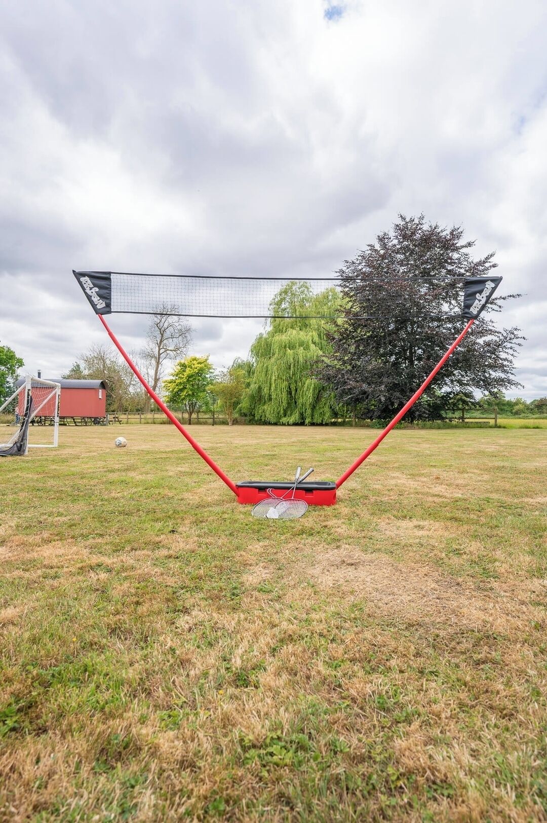 A badminton net set up in an open field with a picnic table and a shed in the background.