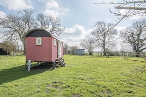 Cozy, single-story dwelling with a pitched roof, situated on a grassy field, offering an and intimate living space.