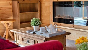 A cozy wooden cabin interior with a wooden table set with white mugs, a teapot, and a small potted plant.