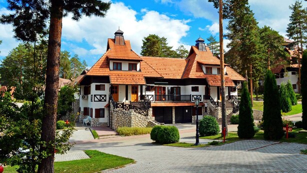A large, two-story house with a red-tiled roof, stone foundation, and a balcony. - Kraljevi Konaci Zlatibor (Zlatibor)