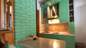 A kitchen with green cabinets, a stainless steel range hood, and a small island with a sink. - Kraljevi Konaci Zlatibor (Zlatibor)