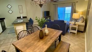 A dining area with a wooden table, chairs, and a bench. There is a chandelier above the table. - Beachfront Condo with Spectacular Views and Heated Pool! (Orange Beach)