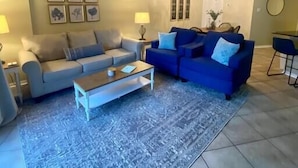 A living room with two sofas, a coffee table, a ceiling fan, and a dining area with chairs and a table. - Beachfront Condo with Spectacular Views and Heated Pool! (Orange Beach)