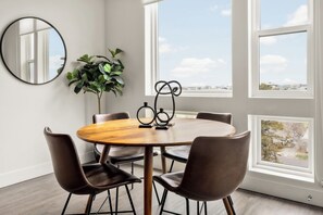 Uma área de refeições com uma mesa redonda, quatro cadeiras, um espelho e um vaso de planta.