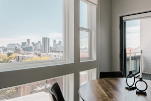 A room with a city view, a round table, and two candle holders. - City Views | Lifestyle Loft | Zuni Lofts (Denver)