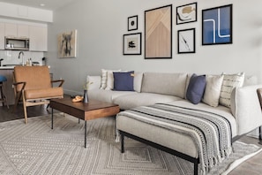 Uma sala de estar moderna com um sofá, poltrona, mesa de centro e um tapete estampado.