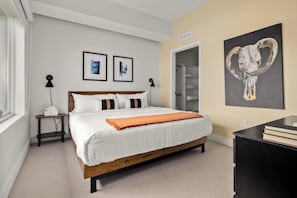 Quarto com cama, mesas de cabeceira, guarda-roupa e obras de arte nas paredes.