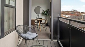 A balcony with a dining area, a chair, and a view of the city. - City Views | Lifestyle Loft | Zuni Lofts (Denver)
