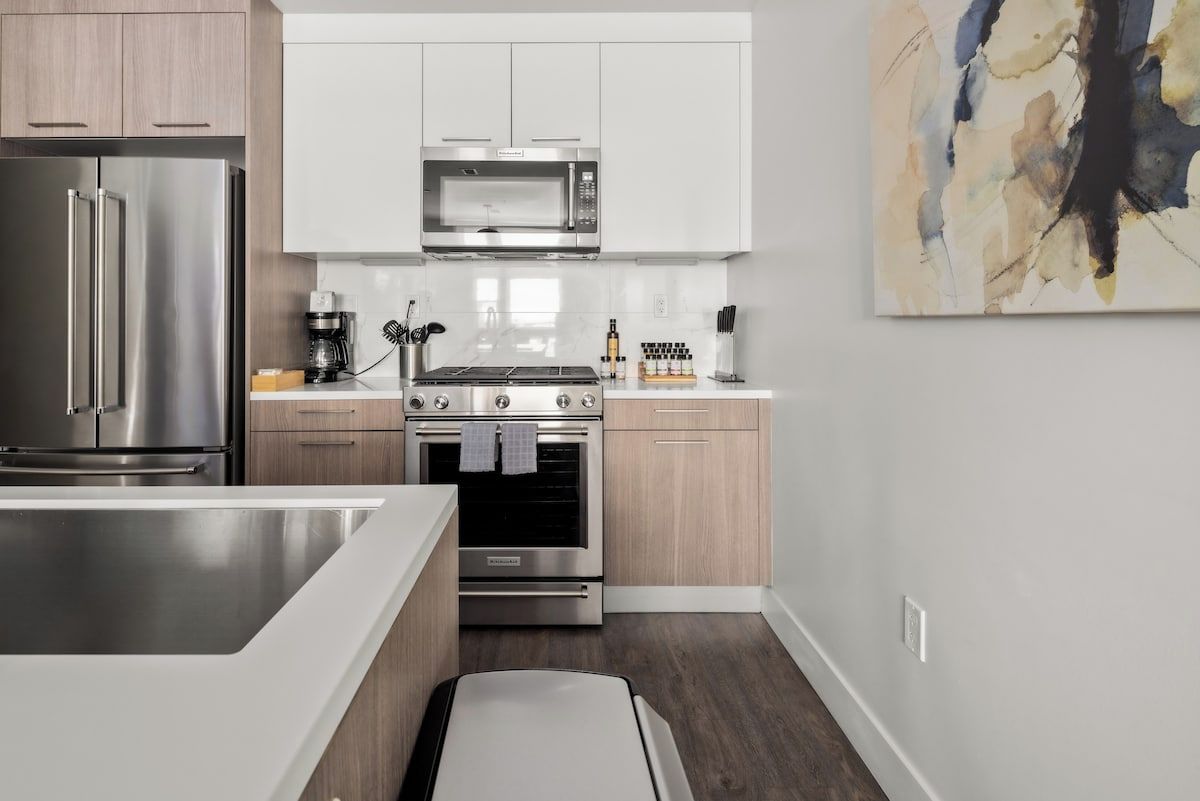 A modern kitchen with stainless steel appliances, wooden cabinets, and a minimalist design.