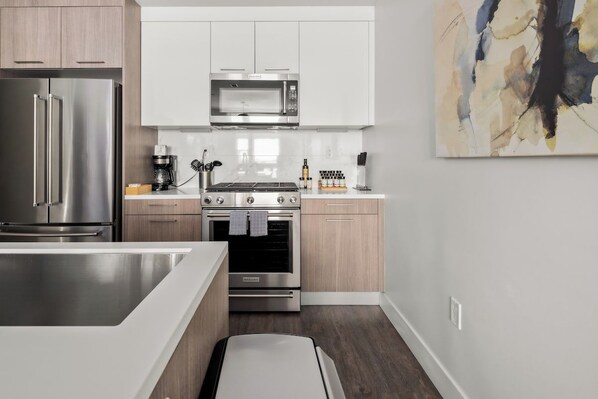 Cozinha moderna com eletrodomésticos de aço inoxidável, armários de madeira e design minimalista.