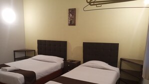 Two single beds with wooden frames and dark headboards in a room with a wooden floor and a plain yellow wall. - EL MONARCA AREQUIPA (Arequipa)