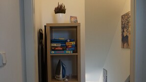 Ein Flur mit einem Holzregal, das Bücher und eine kleine Pflanze beherbergt.
