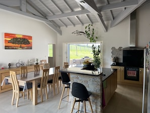A modern kitchen with a stone island, wooden dining set, and a large window offering a view of the outdoors.