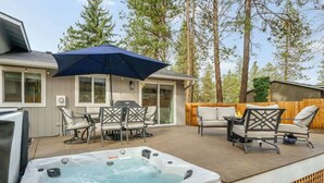 A hot tub on a wooden deck with outdoor furniture and a covered patio area.