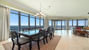 A spacious dining area with a large table and chairs, large windows offering a view of the ocean, and a balcony with a railing. - New to the Rental Market!!  Lazy River, Waterslide!! (Bouvet Island)
