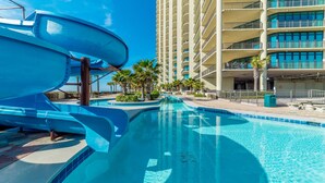A swimming pool with a water slide, palm trees, and a multi-story building in the background. - New to the Rental Market!!  Lazy River, Waterslide!! (Bouvet Island)