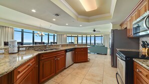 A spacious kitchen with granite countertops, wooden cabinets, and a large island. It features a built-in dishwasher, a refrigerator, and a microwave. - New to the Rental Market!!  Lazy River, Waterslide!! (Bouvet Island)