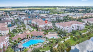 Zona residencial con varios edificios de apartamentos, una piscina y un campo de golf al fondo.