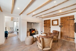 A cozy living room with a fireplace, wooden beams, and rustic furniture.