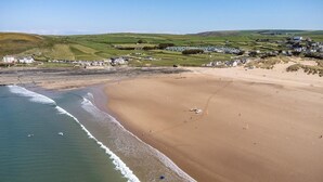 A coastal beach with a sandy shore, waves, and a distant village with houses and fields. - 3 Bed in Croyde (oc-croyco) (Braunton)