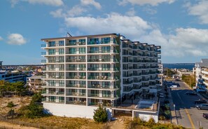 A multi-story hotel with balconies, a swimming pool, and a view of the sea.