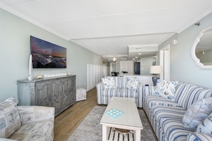 A living room with striped sofas, a coffee table, and a cabinet. - Beautiful condo steps from the beach by Seaside Vacations & Sales (Ocean City)