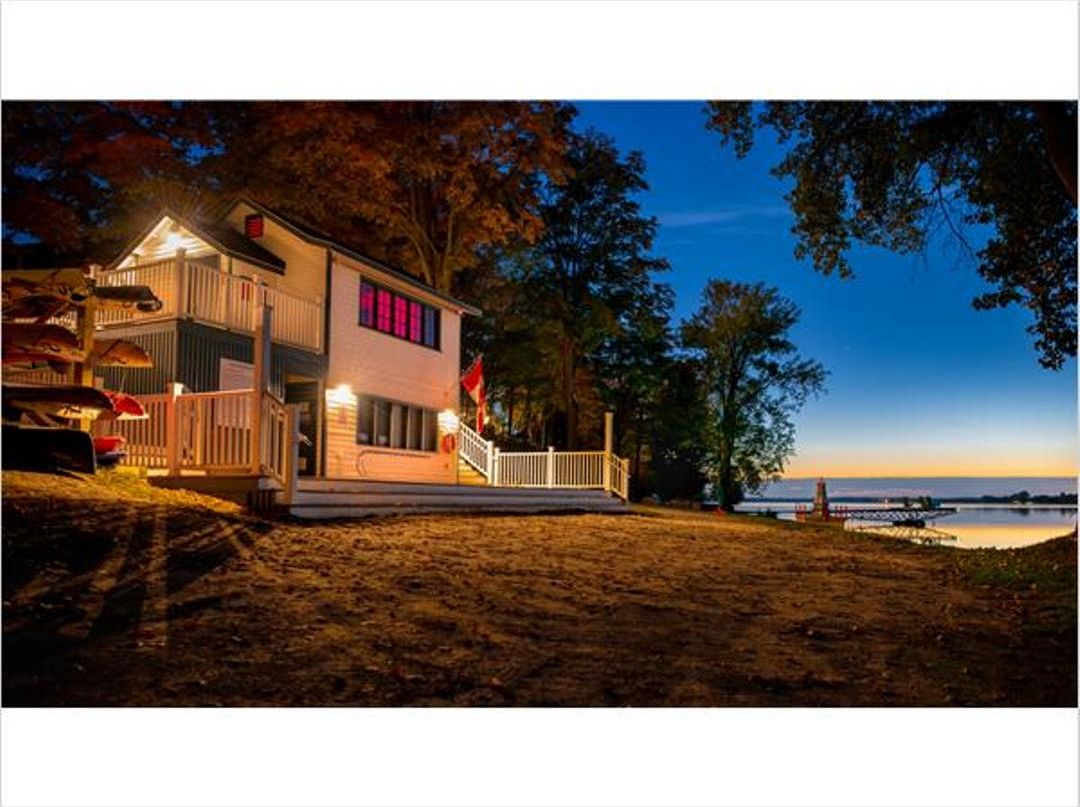 A two-story house with a balcony, a deck, and a view of the water. - Cottage Retreat and Resort Living (Prince Edward)