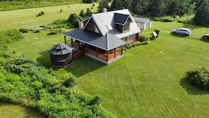 A two-story house with a large deck, a gazebo, and a well-maintained lawn. - 5 Star Log Beach House by the Ocean (Saint Peters Bay)