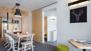 Une cuisine moderne avec des meubles blancs, un plan de travail en bois et un coin repas comprenant une table et des chaises blanches.