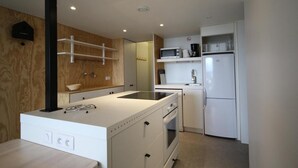 Une cuisine compacte dotée d’un îlot central, d’un four à micro-ondes, d’un réfrigérateur et d’un évier.