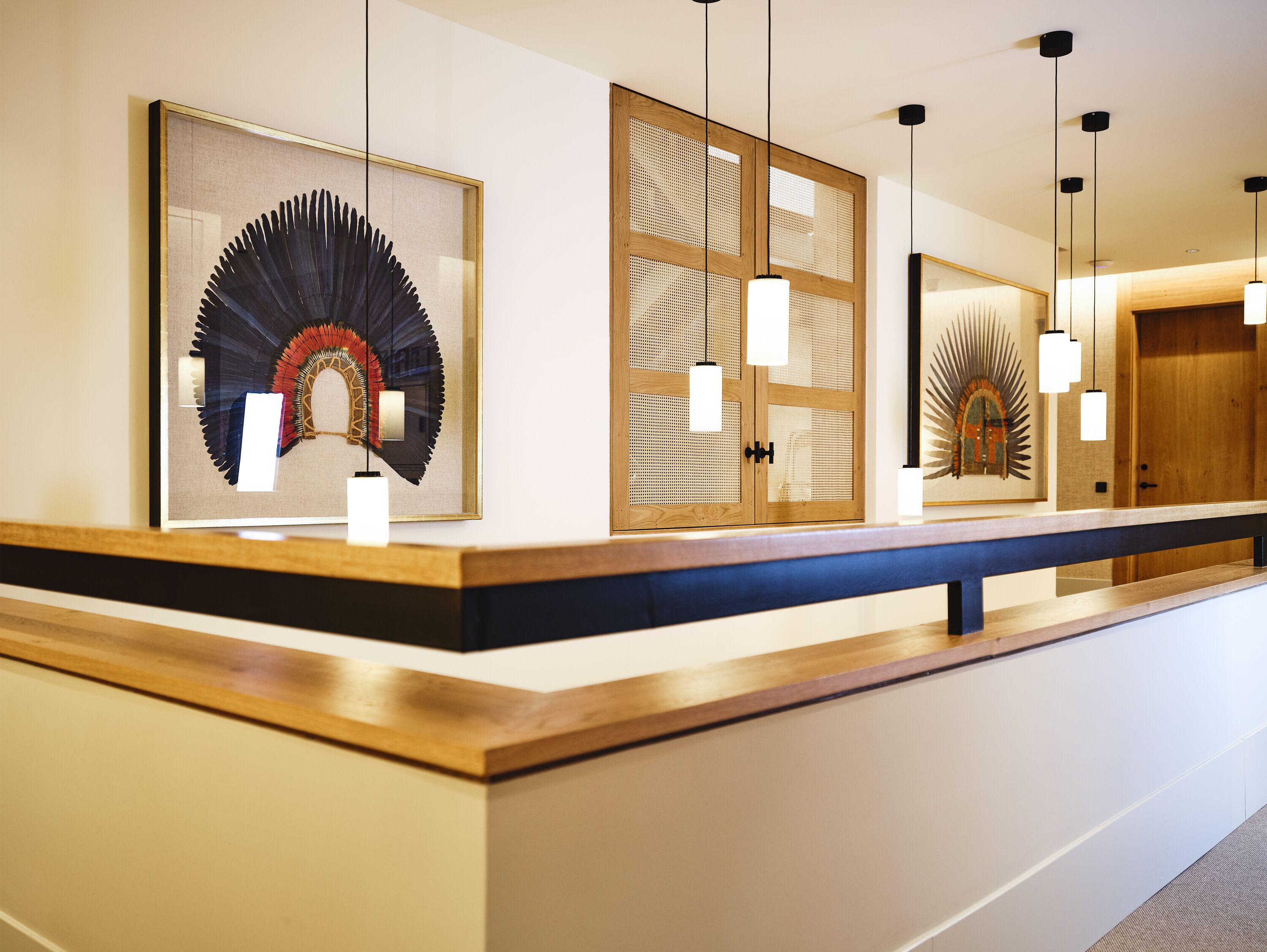 Un área de recepción de hotel con un mostrador de madera, obras de arte enmarcadas en las paredes e iluminación colgante.