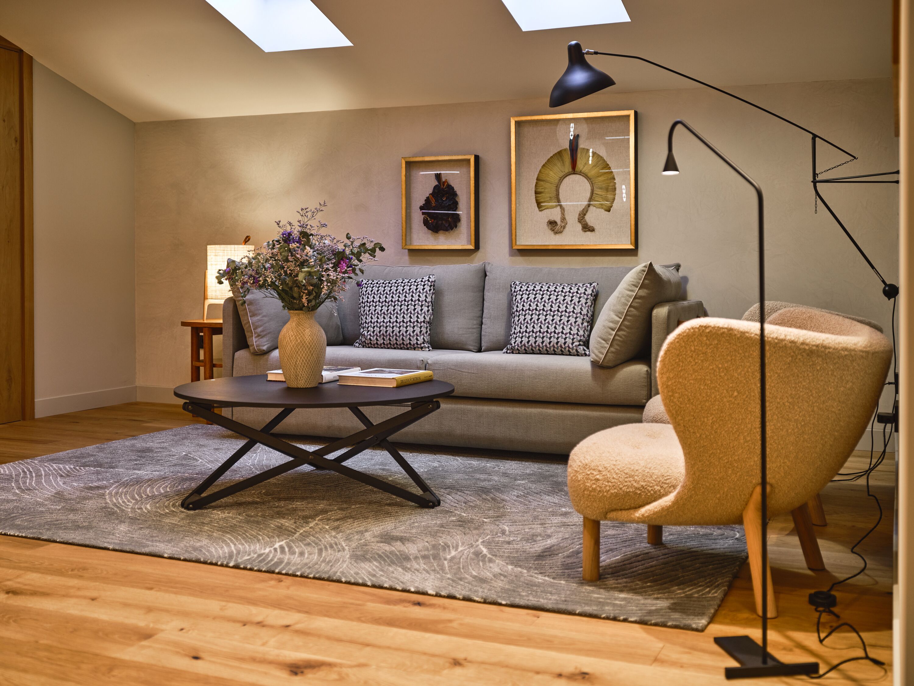 Una sala de estar moderna con un sofá, un sillón, una mesita de centro y una obra de arte en la pared.