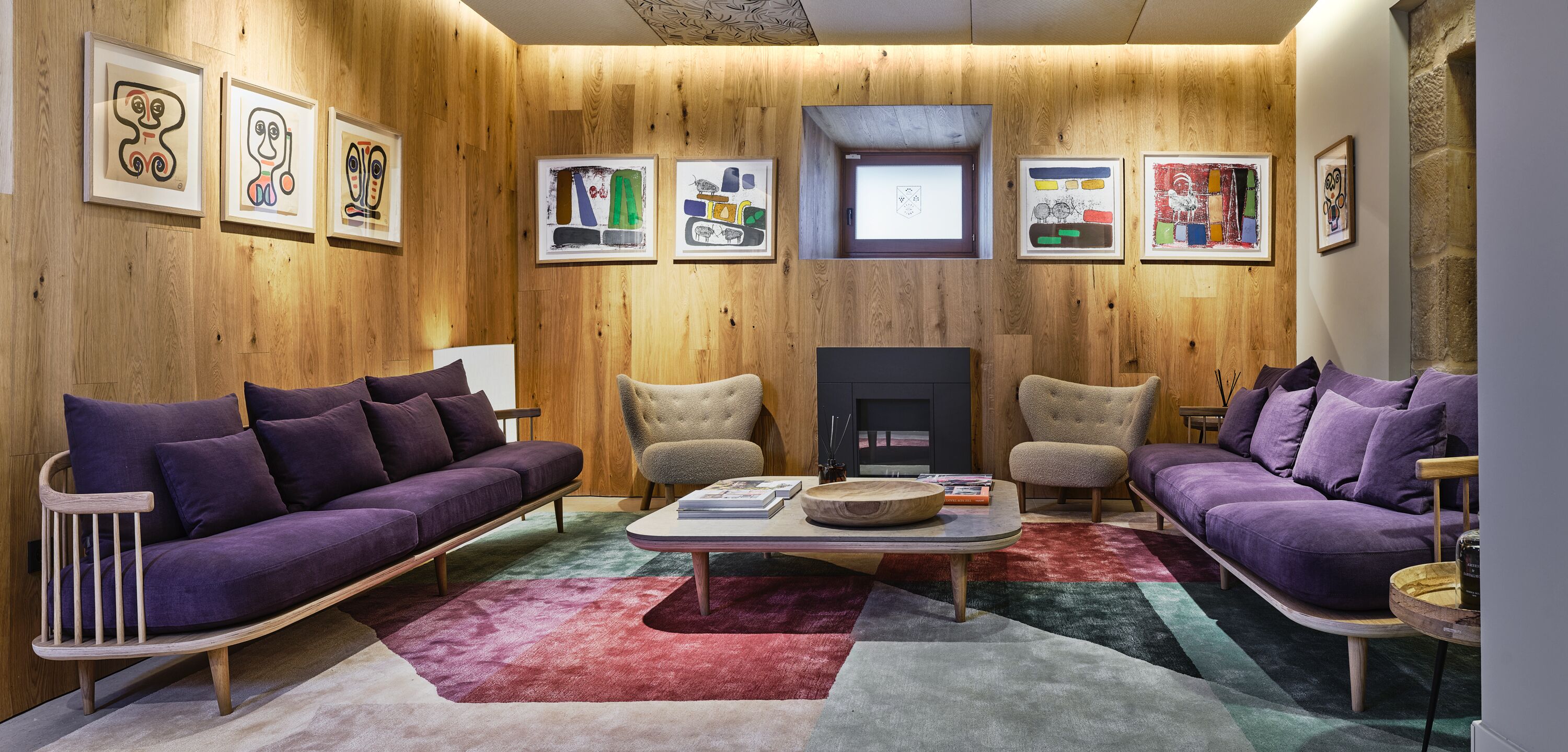 A modern living room with wooden walls, purple sofas, and a central coffee table.