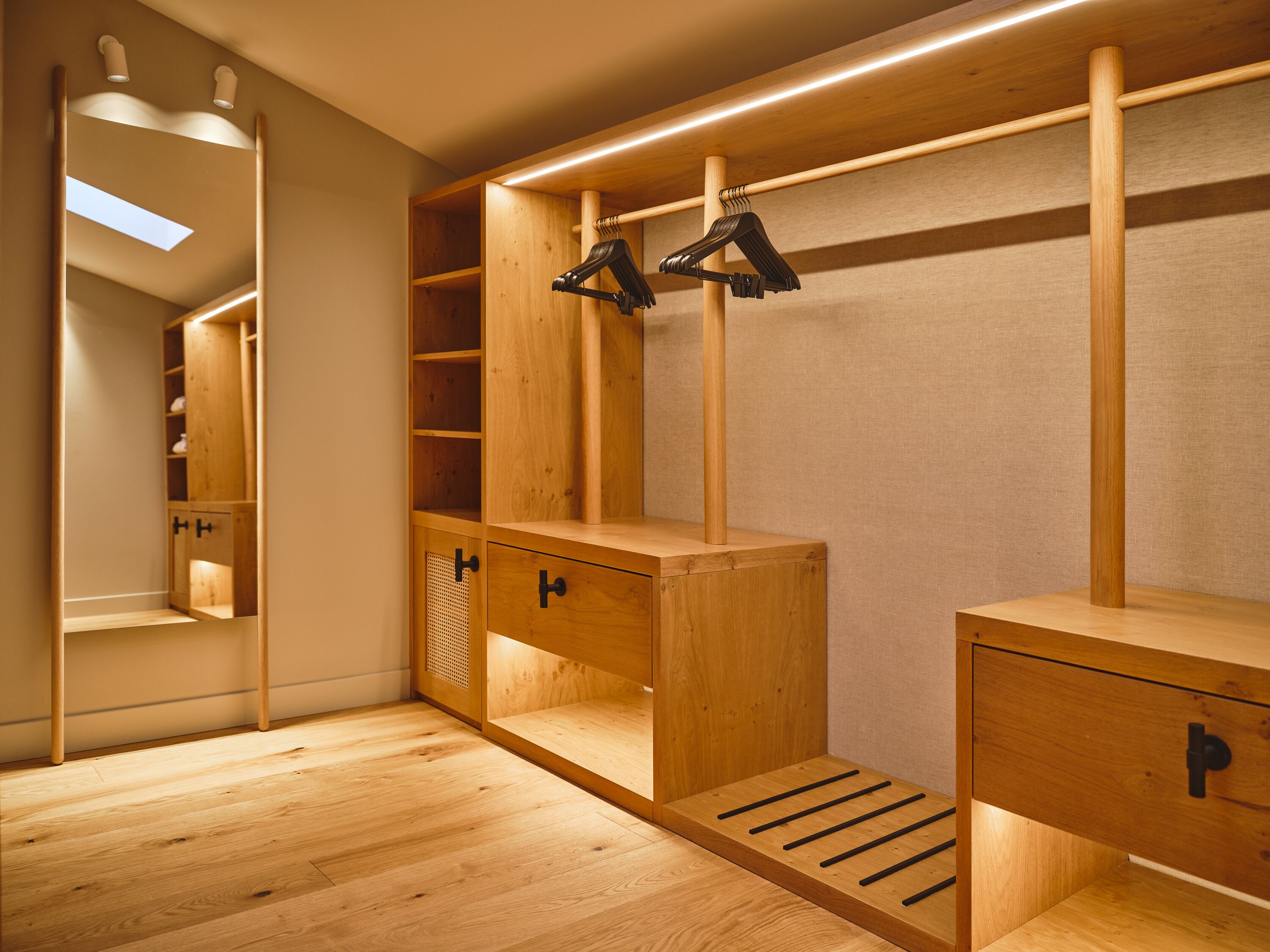 A walk-in closet with wooden shelving, a mirrored wardrobe, and a shoe rack.