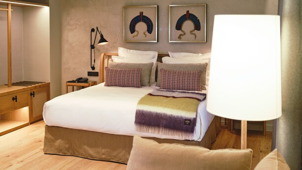 Una camera da letto con un letto grande, comodini, una lampada da comodino, un piccolo tavolo di legno, un tappeto decorato e un divano.