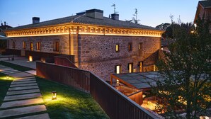 Un edificio in pietra con tetto in tegole, un patio in legno e una scala che conduce a una zona esterna coperta.