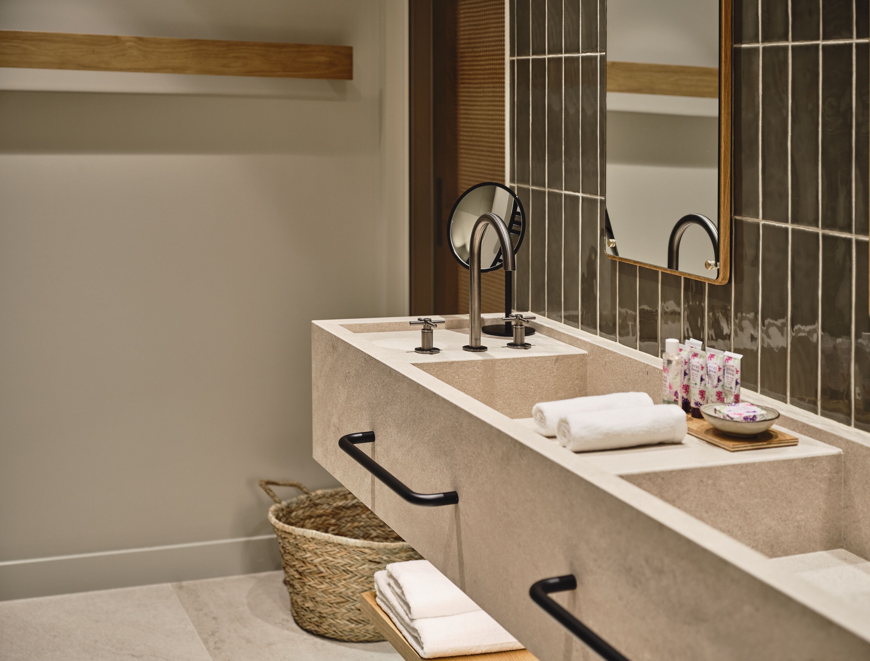 A modern bathroom with a dual sink vanity, a large mirror, and a wicker basket.