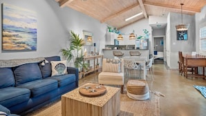Ein geräumiges Wohnzimmer mit einem blauen Sofa, einem Holztisch und einem Essbereich mit Holztisch und Stühlen.