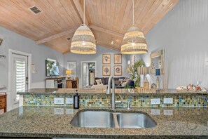 A kitchen with a granite countertop, a stainless steel sink, and a mosaic tile backsplash. - Fun for the Whole Family—Community Pool, Park, and Pet-Friendly Living at Its Best (Port Aransas)