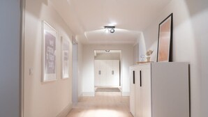 Un couloir doté d’un plancher en bois, de murs blancs et d’une armoire blanche sur laquelle est posée une photo encadrée.