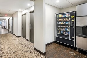 A hotel corridor with a vending machine, doors, and a bench. - Dream Family Vacation! 2 Pet-Friendly Units, Close to Liberty Ride Trolley Tour! (Woburn)