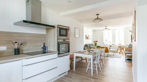 A modern kitchen with white cabinetry, a built-in oven, and a stainless steel range hood.