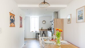 A modern kitchen with a wooden countertop, a dining area with a wooden table, and a view of the adjacent living space.