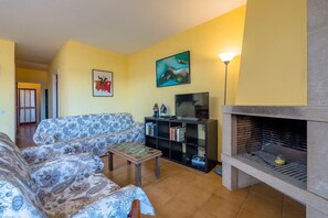 A living room with a sofa, a coffee table, a TV stand, and a fireplace.