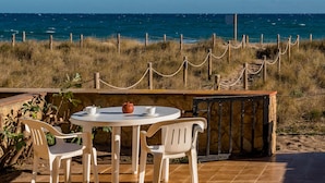 Une table ronde, deux chaises et une théière, le tout installé devant un paysage côtier avec vue sur la mer.