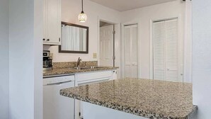 A kitchen with white cabinets, a granite countertop, a sink, and a hanging light fixture. - 4BR Home Minutes to DOWNTOWN, RAD & BILTMORE (Arden)