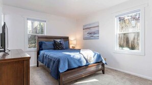 A bedroom with a bed, a nightstand, a TV, and two windows. - 4BR Home Minutes to DOWNTOWN, RAD & BILTMORE (Arden)