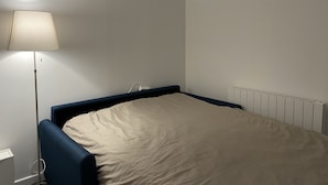 A small, single-bed room with a blue headboard, a bedside table, and a lamp. - #Casamara 1 2-bed apartment | Netflix (Amiens)